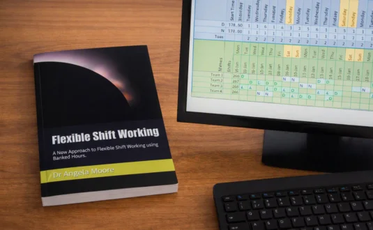 A computer with a shift pattern and a copy of the book Flexible Shift Working next to it